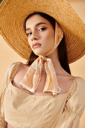 Téléchargez les photos : Une jeune femme aux longs cheveux bruns pose dans un studio, exsudant une humeur estivale avec un chapeau et une écharpe en paille. - en image libre de droit