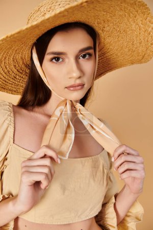 Photo for A young woman with long brunette hair poses in a studio setting, exuding a summer vibe in her straw hat and flowing dress. - Royalty Free Image