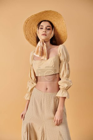 A young woman with long brunette hair strikes a pose in a straw hat, exuding a summery and carefree vibe in a studio setting.