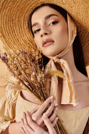 Téléchargez les photos : Une jeune femme aux longs cheveux bruns pose en tenue d'été, portant un chapeau de paille et tenant un bouquet de fleurs. - en image libre de droit