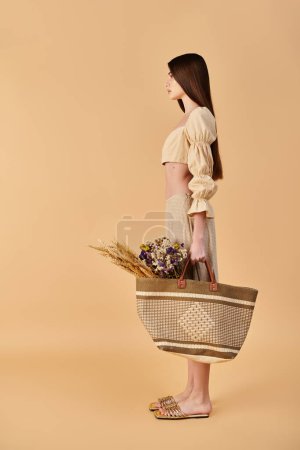 A young woman with long brunette hair elegantly holds a basket filled with colorful flowers, exuding a vibrant summer mood.