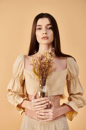 Téléchargez les photos : Une jeune femme aux longs cheveux bruns pose en tenue d'été, tenant un bouquet de fleurs vibrant. - en image libre de droit