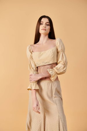 Foto de Una mujer joven con el pelo largo y morena posa con gracia en un traje de verano de una falda y un top recortado - Imagen libre de derechos