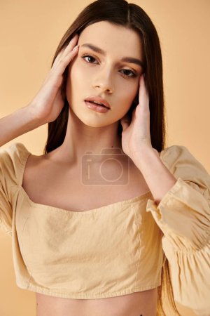 Eine junge Frau mit langen brünetten Haaren nimmt eine selbstbewusste Pose ein und präsentiert ein Sommer-Outfit in einem Studio-Setting.