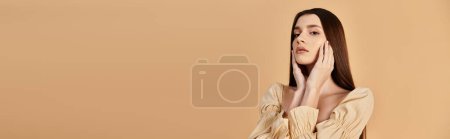 Photo for A young woman in a dress poses with hands covering her face in a studio, exuding summer vibes. - Royalty Free Image