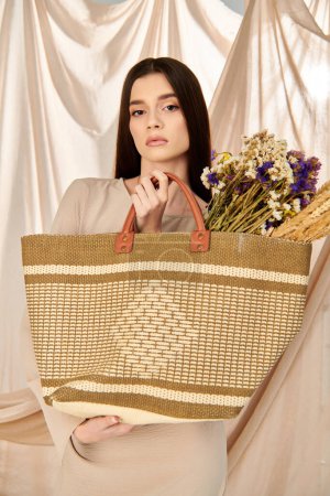 A young woman with long brunette hair embraces the essence of summer, holding a large woven bag in a serene pose in a studio setting.