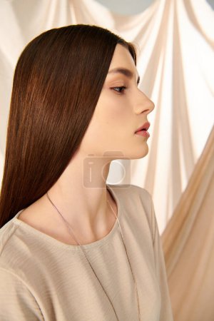 Une jeune femme aux longs cheveux bruns pose devant un rideau, respirant une ambiance estivale dans un décor de studio.