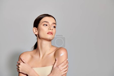 Une jeune femme aux cheveux bruns pose en toute confiance les bras croisés dans un élégant portrait studio.
