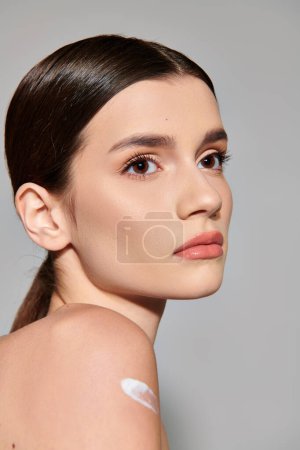 A young woman with brunette hair showcasing elaborate makeup in a studio setting, exuding female beauty and style.