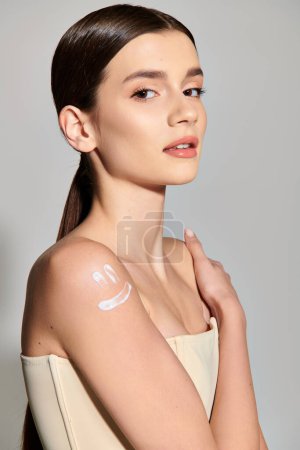 Photo for A young woman with brunette hair stands in a studio setting, her arm adorned with an abundant amount of cream. - Royalty Free Image