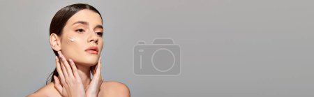 Photo for A young woman with brunette hair gently touches her face with her hands, displaying a moment of introspection and beauty. - Royalty Free Image