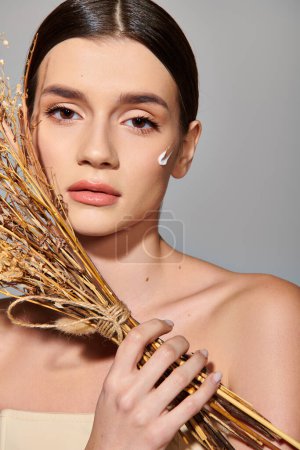 Photo for A graceful young woman with brunette hair holds a bunch of dry flowers in a studio setting, exuding natural beauty and serenity. - Royalty Free Image