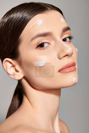 Photo for A young brunette woman poses with a generous amount of cream on her face, exuding beauty and luxury. - Royalty Free Image