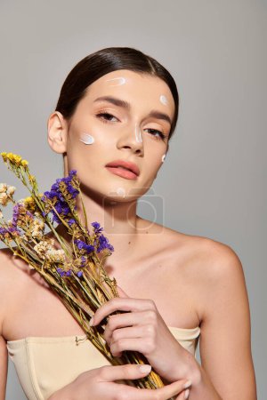Photo for A young woman with brunette hair joyfully holds a bunch of flowers, her face adorned with plenty of cream. - Royalty Free Image