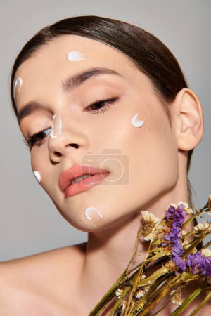 A young woman with brunette hair showcases her beauty with white dots adorning her face in a serene studio setting.
