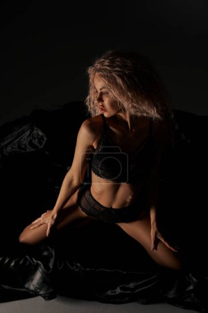 Photo for A seductive woman in lingerie sitting provocatively on a bed, exuding confidence and allure. - Royalty Free Image