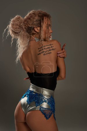 Téléchargez les photos : Une jeune femme séduisante avec un tatouage sur le dos posant allègrement. - en image libre de droit