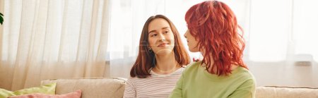 Dos jóvenes lesbianas compartiendo un momento tierno en un sofá acogedor, pareja encerrada en una pancarta de amor