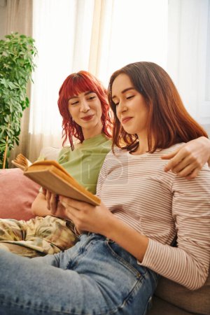 cheerful lesbian couple enjoying quiet moment of reading together, wrapped in love and comfort