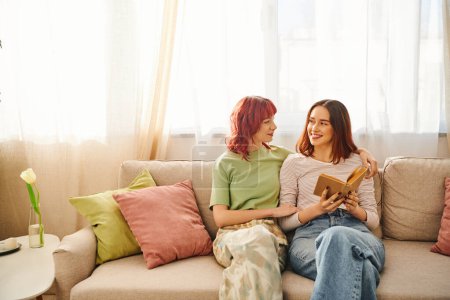 glückliches lesbisches Paar mit Buch genießt ruhigen Moment und schaut einander an, Liebe und Komfort