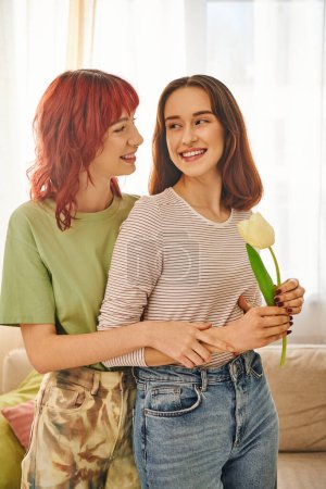 Photo for Tender moment of lesbian woman holding tulip and hugging happy girlfriend, symbol of spring and love - Royalty Free Image