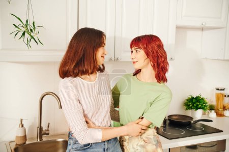 Téléchargez les photos : Intimate kitchen scene with a loving young lesbian couple sharing a moment of connection, embrace - en image libre de droit