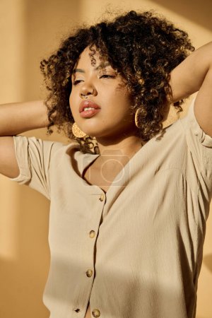 Eine schöne junge Afroamerikanerin mit lockigem Haar in einem Sommerkleid posiert selbstbewusst für ein Fotoshooting in einem Studio.