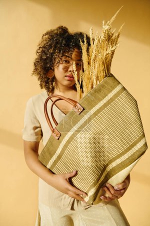 Eine schöne junge Afroamerikanerin mit lockigem Haar hält einen Korb Weizen in ihren Händen, der Fülle und Ernte verkörpert.