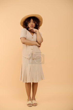 A beautiful young African American woman with curly hair wearing a hat and summer dress in a studio setting.