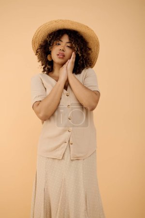 A beautiful young African American woman with curly hair wearing a summer dress and hat in a studio setting.