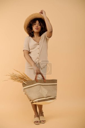 Photo for A beautiful young African American woman with curly hair holds a basket and a straw hat in a studio setting. - Royalty Free Image