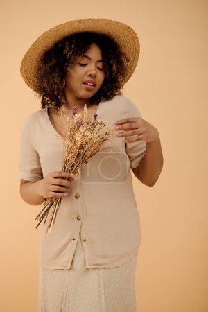 Foto de Una mujer afroamericana con estilo en un sombrero con gracia sostiene un ramo de flores vibrantes en un entorno de estudio. - Imagen libre de derechos