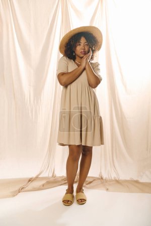 Eine schöne junge Afroamerikanerin mit lockigem Haar, trägt ein Sommerkleid und einen Hut und posiert für ein Foto.