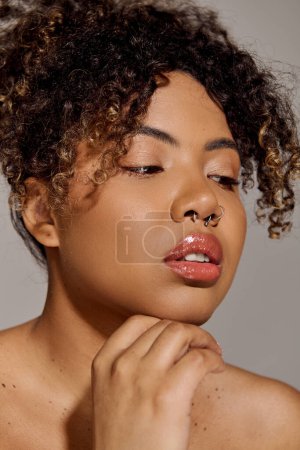 Stunning African American woman with curly hair exuding grace and beauty in a studio setting.