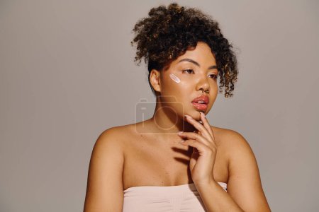 Photo for Young African American woman with curly hair, peacefully holds hand to face in a studio setting. - Royalty Free Image