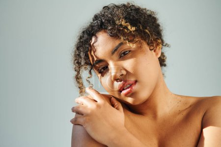 Eine lebendige, schöne Afroamerikanerin mit lockigem Haar posiert selbstbewusst.