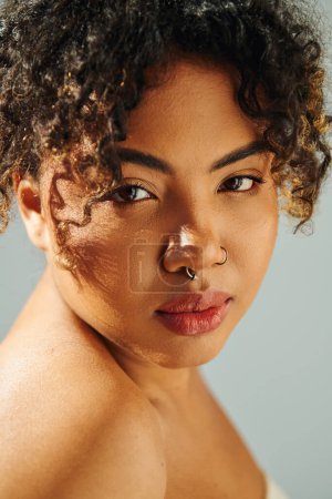 A beautiful African American woman posing with a striking nose ring against a vibrant backdrop.