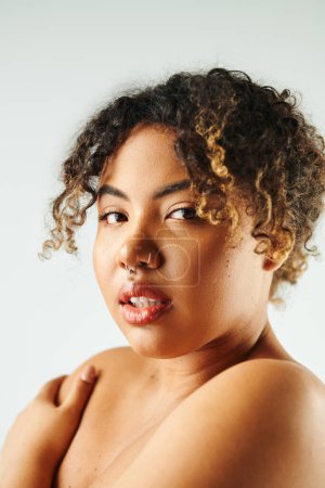 Foto de Primer plano de la vibrante mujer afroamericana con el pelo rizado posando con confianza. - Imagen libre de derechos
