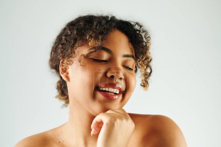 Mujer afroamericana con los ojos cerrados, la mano bajo la barbilla, posando serenamente.