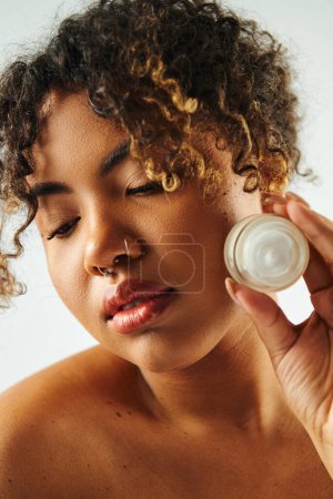Photo for African American woman showcasing cream jar. - Royalty Free Image