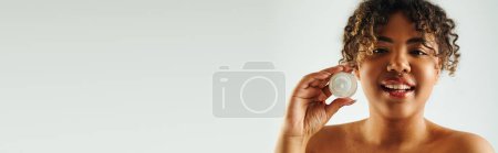 Photo for Alluring African American woman showcasing cream jar. - Royalty Free Image