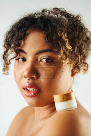 Foto de Hermosa mujer afroamericana mostrando tarro de crema. - Imagen libre de derechos