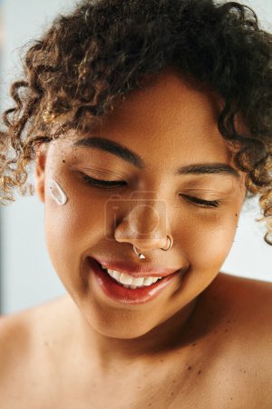 Primer plano de una mujer afroamericana con un anillo en la nariz sobre un vibrante telón de fondo.