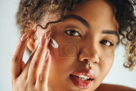 Close-up of African American woman delicately touching her face.