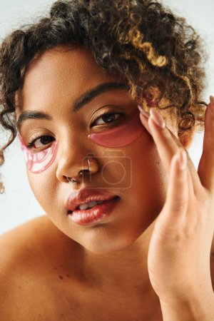 A close-up view of a beautiful African American woman showcasing eye patches on a vibrant backdrop.