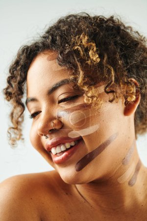 Schöne Afroamerikanerin mit einem Fundament im Gesicht posiert vor lebendiger Kulisse.
