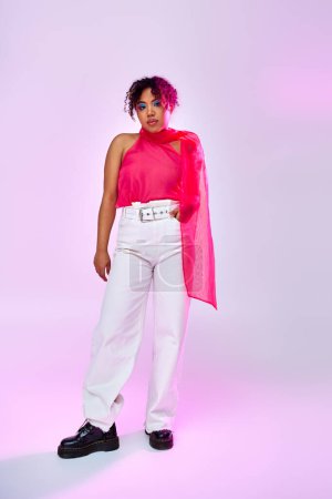 Elegant woman poses in stylish white pants and pink top on vibrant backdrop.