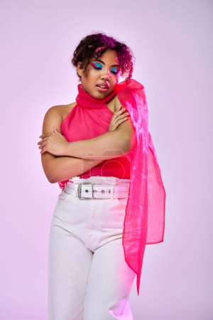 African American woman energetically poses in white pants and pink top against vibrant backdrop.