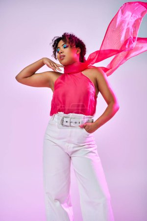 Una hermosa mujer afroamericana posa activamente en un top rosa y pantalones blancos sobre un vibrante telón de fondo.
