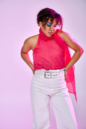 Mujer afroamericana posando en pantalones blancos, top rosa.